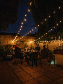 People dining al fresco outside underneath beautiful twinkling string lights from Stellar Lighting
