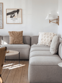 A grey Scandinavian couch with neutral throw cushions and art of the walls.