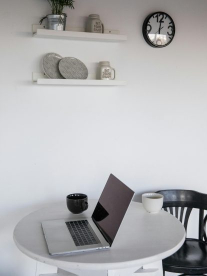 A Macbook on a white round table in a minimalistic home.